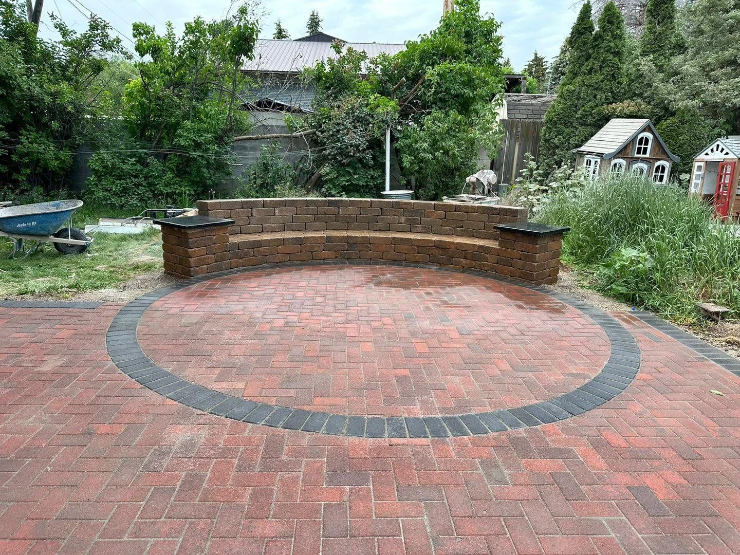 Red brick paver patio with a curved block seat wall and contrasting border