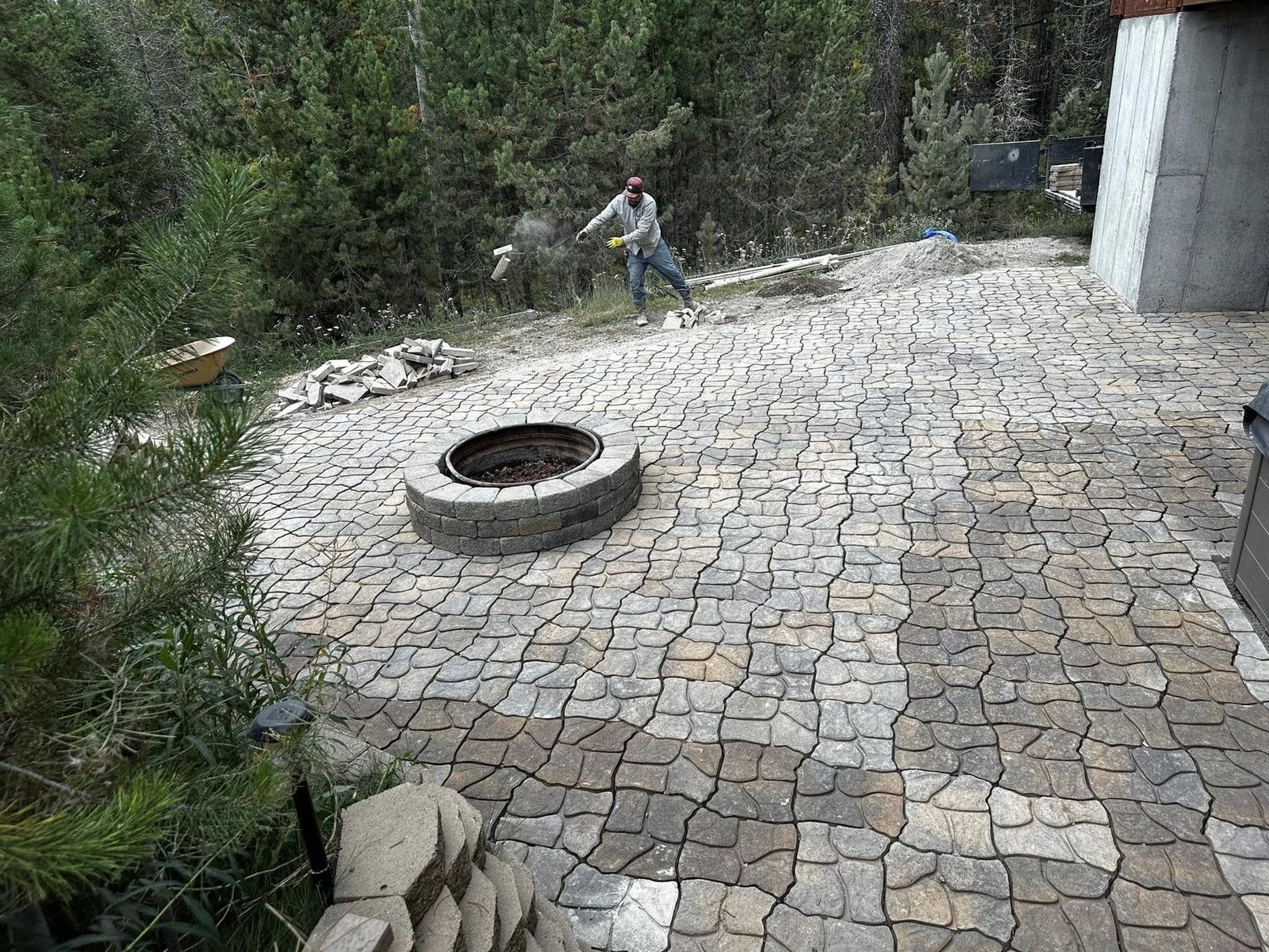 High Quality Pavers crew spreading joint sand on a cobble paver patio with firepit