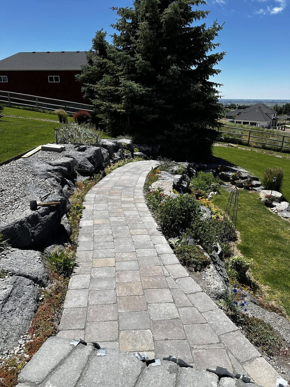 Curved cobble paver garden path through landscaped beds with valley views